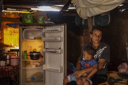A desempregada Rosangela da Silva, 36, com seu filho Artur, 3, no colo perto da geladeira quase vazia dentro de seu barraco no Jardim Papai Noel, em São Paulo